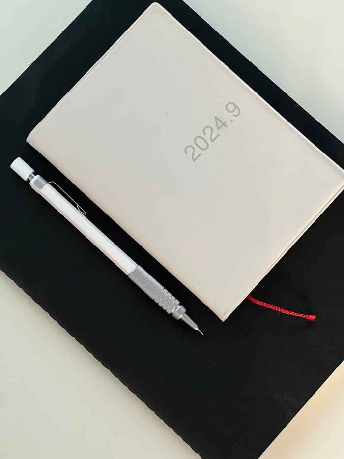 A clean, minimalist setup featuring a diary marked 2024.9 along with a mechanical pencil on a desk.